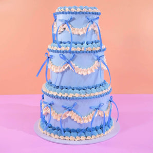 3 Tier Vintage Cake by Crumbs & Doilies, decorated with blue and white piped icing and ribbon accents.